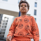 Toddler wearing the NAADA basketball sweatshirt and joggers set on a court