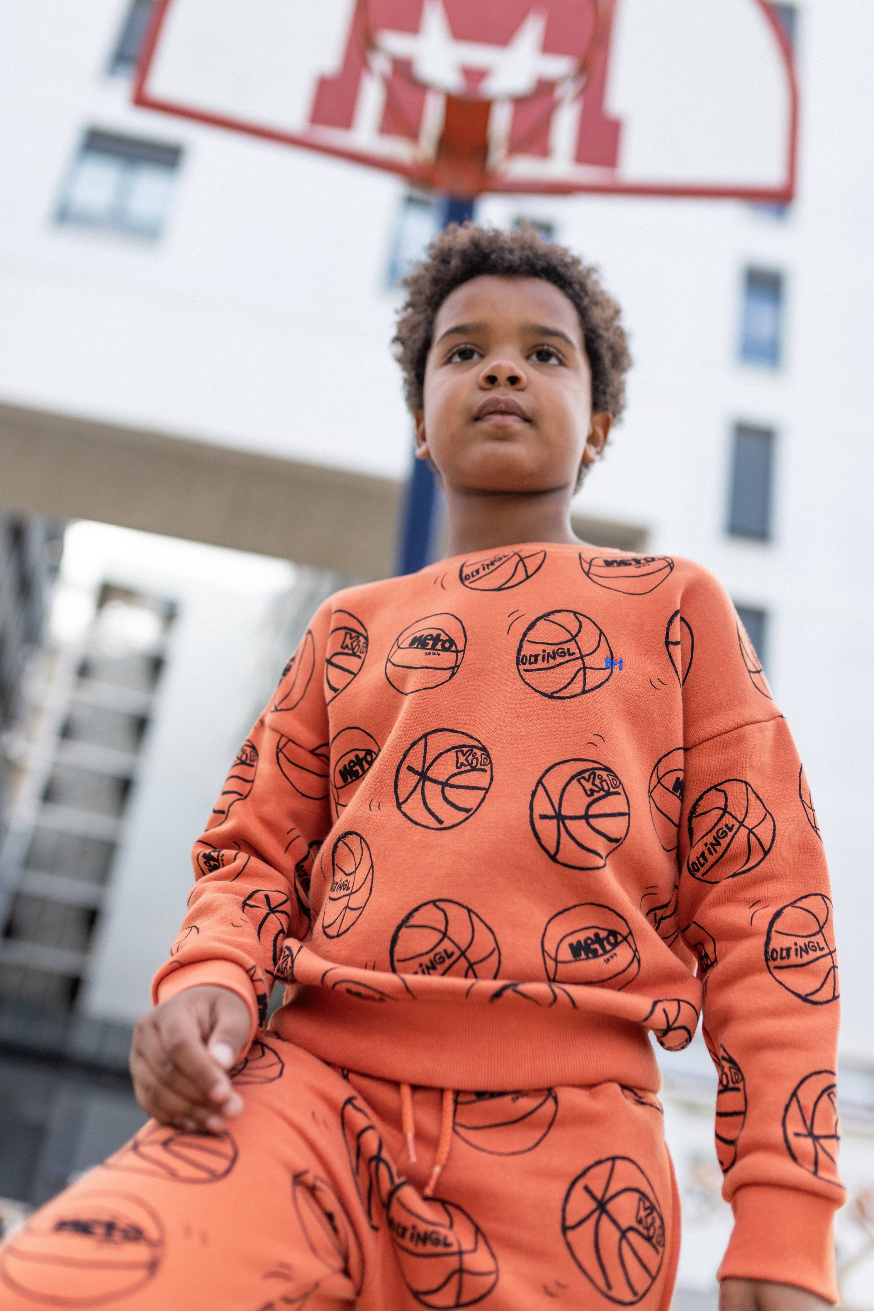 Toddler wearing the NAADA basketball sweatshirt and joggers set on a court