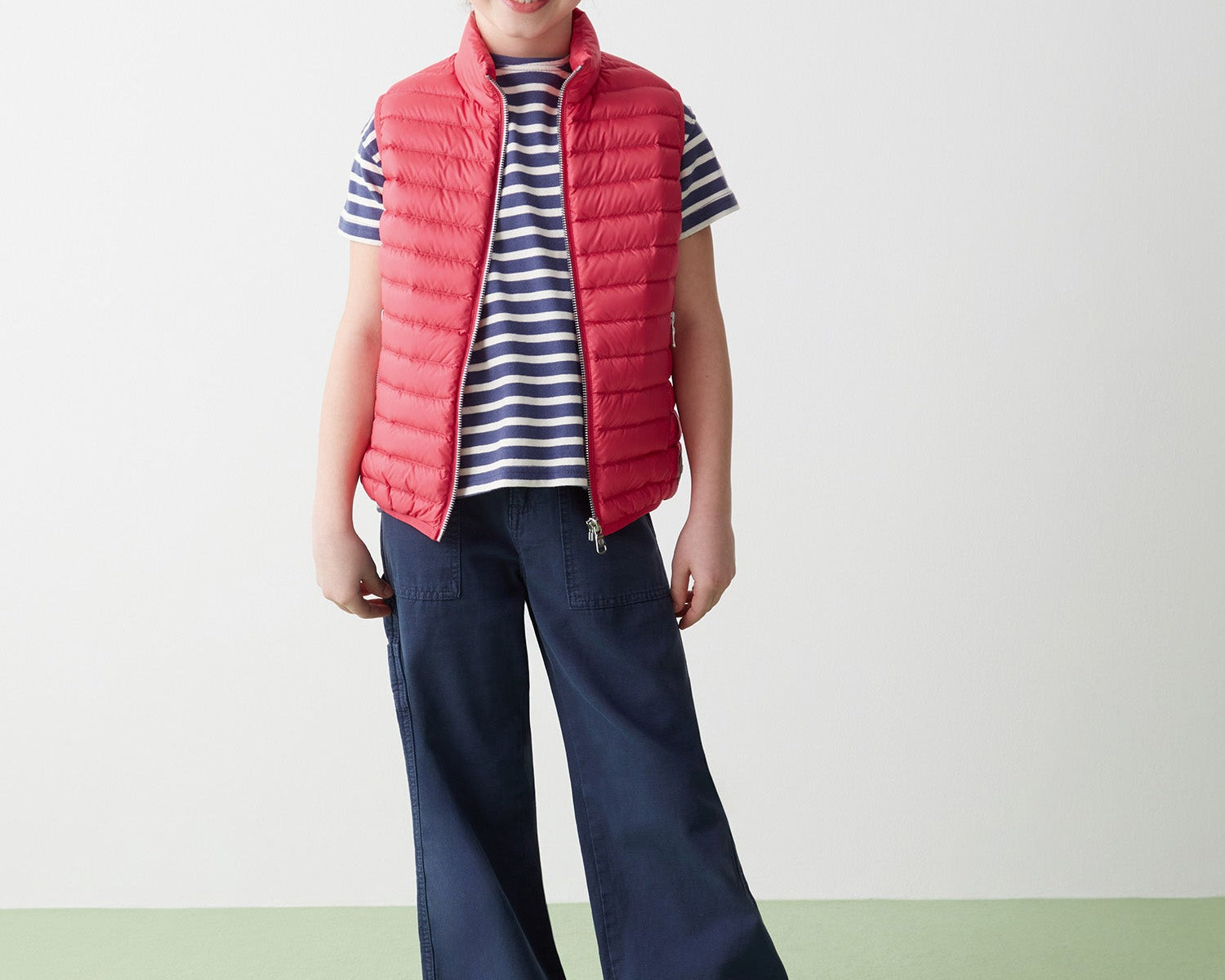 Girl in red sleeveless recycled jacket and navy pants