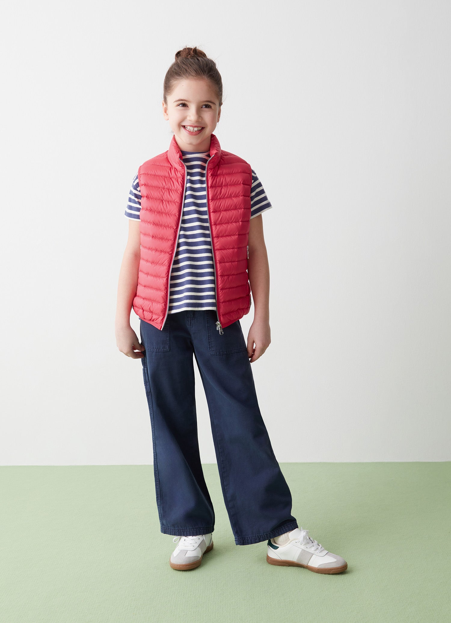 Girl in red sleeveless recycled jacket and navy pants