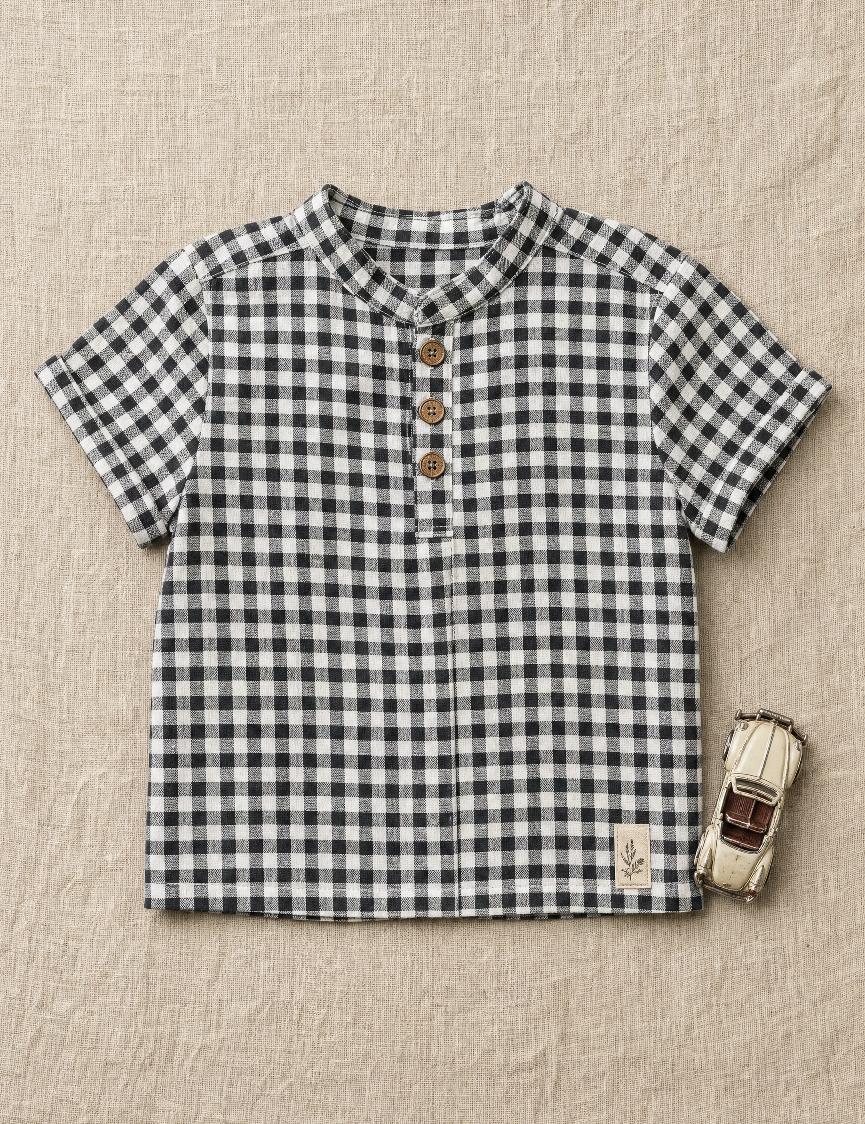 Gingham toddler shirt with a band collar laid flat on linen